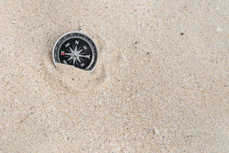 front view from above of a compass on the sand of a beach in daylight