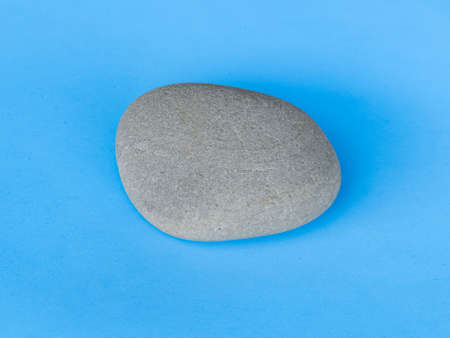gray stone isolated on blue background top viewの写真素材
