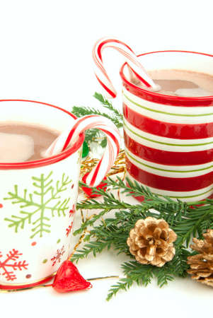 Two Christmas cups with Hot cocoa, candy canes, decorated with candies, cones and isolated on a white backgroundの写真素材