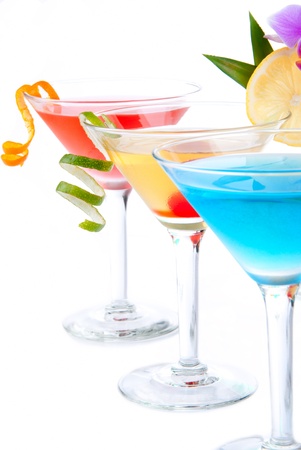 Summer Tropical Martini Cocktails with vodka, apple and peach liqueur, pineapple and cranberry juice, lime, lemon, blue curacao, maraschino cherry, and orchid isolated on a white backgroundの写真素材
