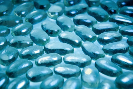 Heap of blue bright glass pebble stones on a turquoise background の写真素材