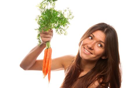 Young healthy woman holds in right hand bunch fresh orange organic carrots with green leaves from the garden isolated on a white backgroundの写真素材
