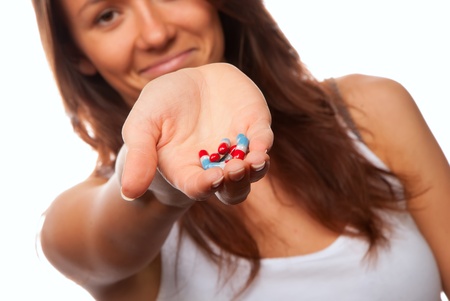 Young woman doctor offering pill capsules red and blue to the patient in hand isolated on a white backgroundの写真素材