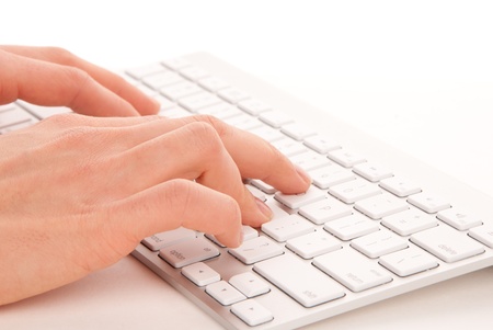  Hands typing on the remote wireless computer keyboard in an office at a workplace isolated on a white backgroundの写真素材