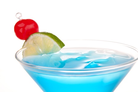 Blue Cosmopolitan cocktail with vodka, blue curacao, white cranberry juice, lime, crushed ice and maraschino cherry in chilled martini glass isolated on a white backgroundの写真素材