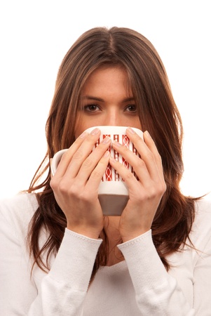 Pretty young woman holding red pattern mug of tea / coffee in hands isolated on white backgroundの写真素材