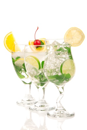 Citrus Mojito cocktails with light rum, vodka, gin, lime, spring of mint, simple soda, orange, maraschino cherry and syrup in cocktail glasses isolated on a white backgroundの写真素材