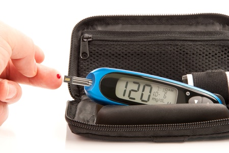 Diabetic patient doing glucose level blood test using ultra mini glucometer kit and small drop of blood from finger and test strips isolated on a white background. Device shows 120  mg/dL which is normal の写真素材