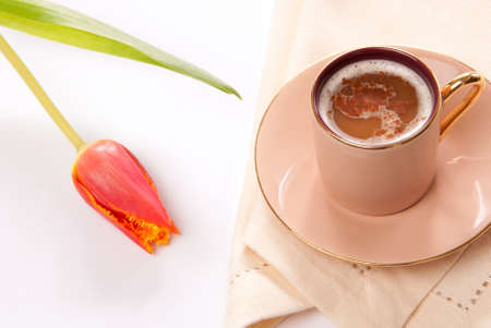 Cappuccino or espresso coffee in a cup with frothed milk and spring tulip flower on a white background の写真素材