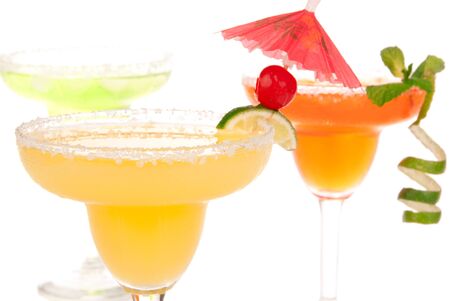Yellow margarita cocktails in chilled salt rimmed glasses with tequila, triple sec, juice, simple syrup and crushed ice garnished slice of fresh lime in margaritas glass isolated on white backgroundの写真素材