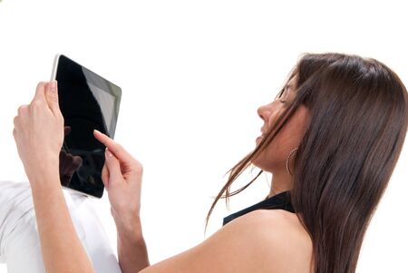Young brunette woman sitting, holding her new black modern electronic tablet, device, pc, touch pad, computer in hands, one finger touching the digital screen isolated on a white background の写真素材