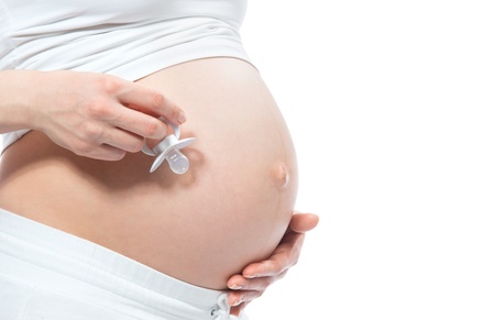 Pregnant woman hold abdomen baby's dummy in hands isolated on a white background