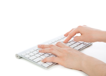 Hands typing on the remote wireless computer keyboard in an office at a workplace isolated on a white backgroundの写真素材