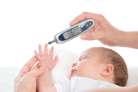 Doctor hand measuring glucose level blood chemistry test from a baby using glucometerの写真素材