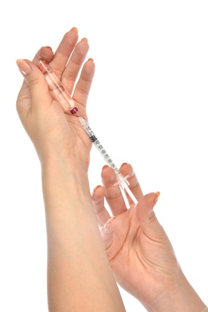 Doctor hands with medical syringe with needle in ampule getting ready for patient injection isolated on a white backgroundの写真素材