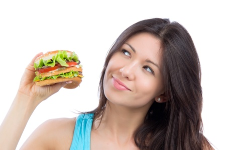 Young woman with tasty fast food unhealthy burger in hand to eat isolated on a white backgroundの写真素材