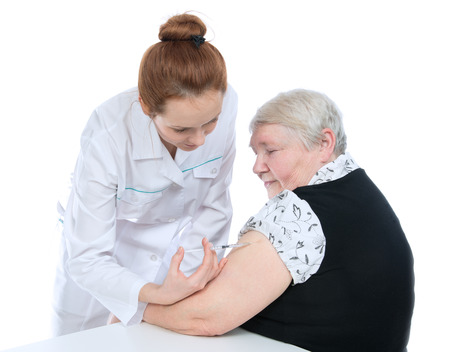 Doctor making senior woman patient an arm subcutaneous insulin medicine syringe injection vaccination shot on a whiteの写真素材