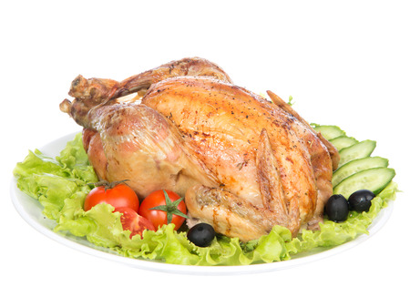 Garnished roasted thanksgiving chicken on a plate decorated with salad, olives, tomatoes, cucumbers isolated on a white の写真素材