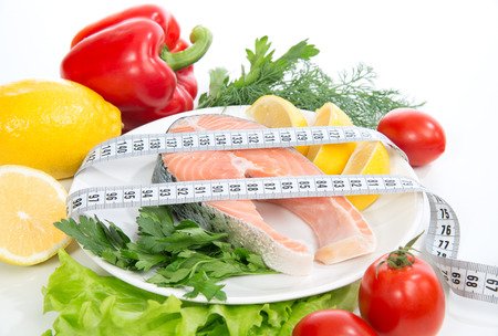 Diet weight loss concept. Fresh salmon steak for lunch with tape measure centimetrの写真素材