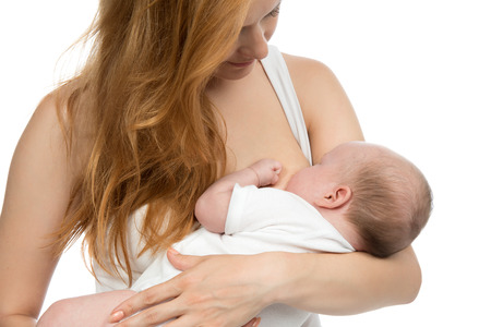Young mother woman breastfeeding her infant child baby girl lying on her breast and feeding on a...