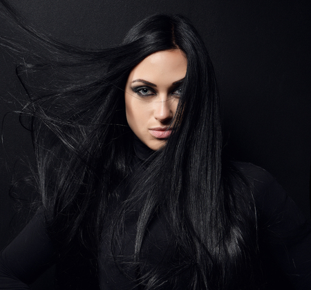 Beautiful brunette girl with healthy long hair and blue eyes on black backgroundの写真素材