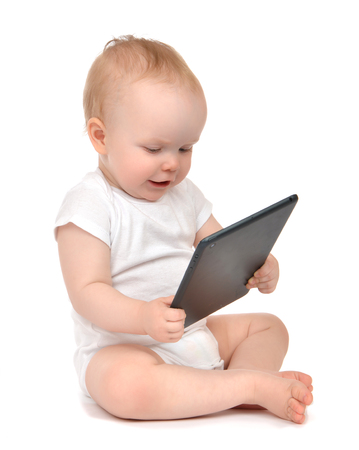 Infant child baby toddler sitting and typing digital tablet mobile computer isolated on a white backgroundの写真素材