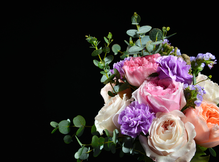 Beautiful bouquet of bright white pink purple roses flowers with green leafs on black backgroundの写真素材
