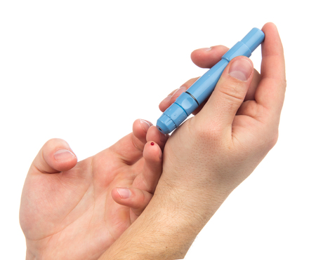 Diabetes lancet in hand prick finger to make punctures to obtain small blood specimens for blood glucose level test using glucometer isolated on a white backgroundの写真素材