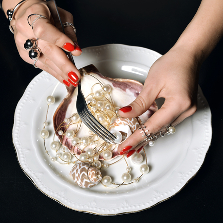 Beautiful woman hands with red pattern polish manicured nails and silver stacking rings and...