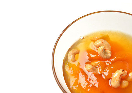 Sweet apricot jam in the transparent glass bowl with cashew nuts and text copy space on a white backgroundの写真素材