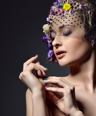 Beautiful young fashion woman portrait with delicate flowers in hair with flower wreath closeup on dark backgroundの写真素材