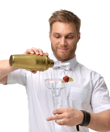 Bartender men is preparing red margarita cocktail with strawberry and lime. Hold empty glass and gold shaker isolated on a white backgroundの写真素材
