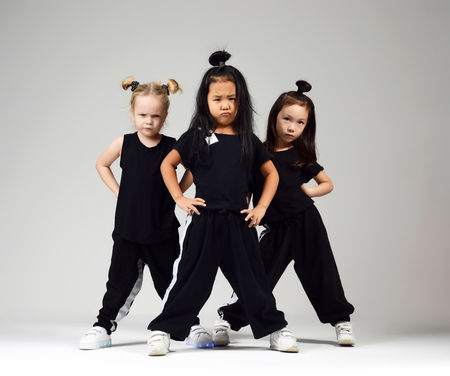 Group of three young girl kids hip hop dancers on gray background