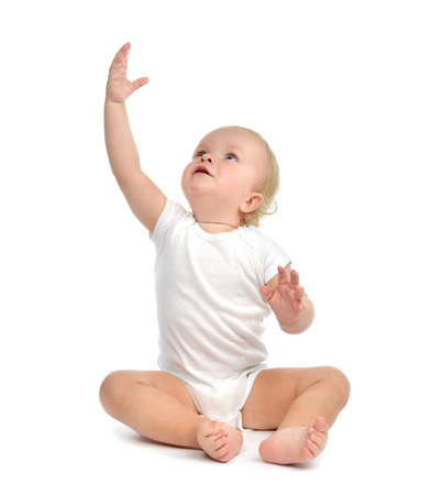 Infant child baby toddler sitting hands up isolated on a white backgroundの写真素材