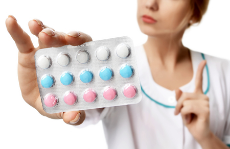 Female doctor offering pack of pills capsules blue to the patient in hand isolated on a white background. Focus on tabletsの写真素材