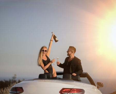 Young couple have holiday party drinking champagne at the beach cheers at sunriseの写真素材