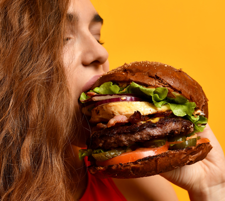 Tasty unhealthy burger sandwich in woman hands hungry mouth getting ready to eat isolated on a white background. Fast food concept.の写真素材