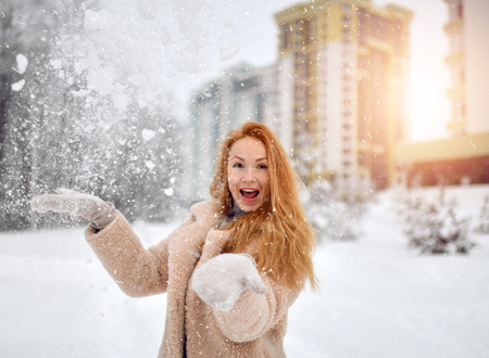 Beautiful woman in the winter scenery under heavy snow in urban city houses backgroundの写真素材