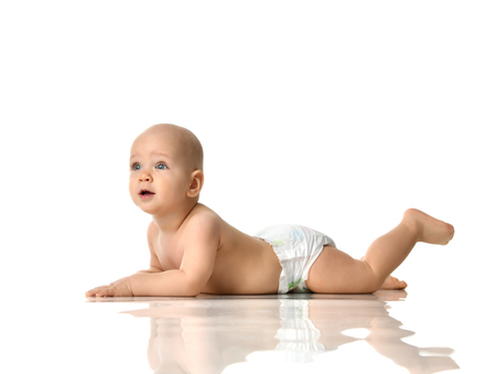 Infant child baby  lying naked in diaper on the floor and looking at the corner isolated on a white backgroundの写真素材