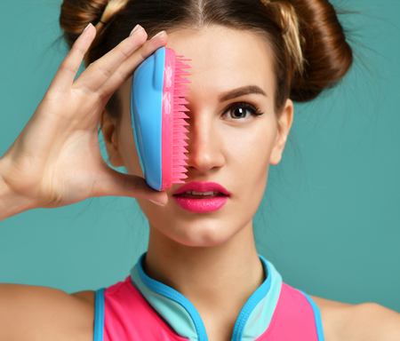 Closeup portrait of happy fashion brunette woman close eye with colorful pink blue popular hair comb brush on modern mint backgroundの写真素材