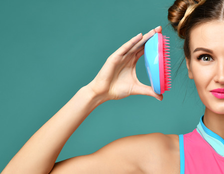 Closeup portrait of happy fashion brunette woman close eye with colorful pink blue popular hair comb brush on modern mint backgroundの写真素材