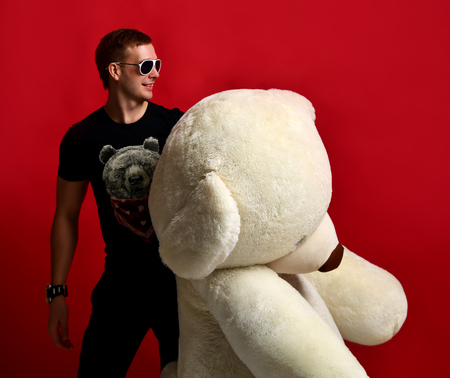Man hold big teddy bear soft toy as a present to his girlfriend for birthday party on red backgroundの写真素材
