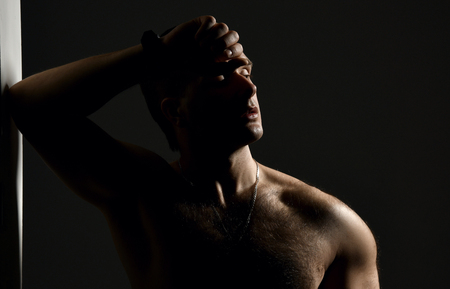 Closeup portrait of sexy handsome topless male model on dark black backgroundの写真素材