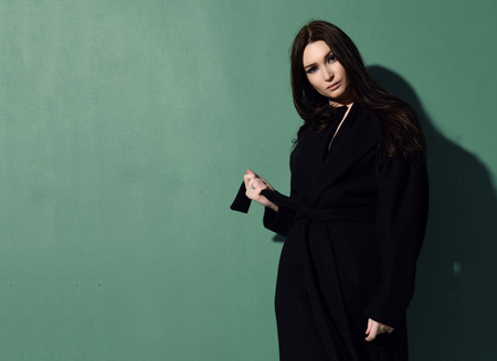 Beautiful brunette woman with long hair posing on green mint backgroundの写真素材