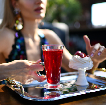 Beautiful woman in expensive interior restaurant  cafe drinking red margarita cocktail or juice tea...