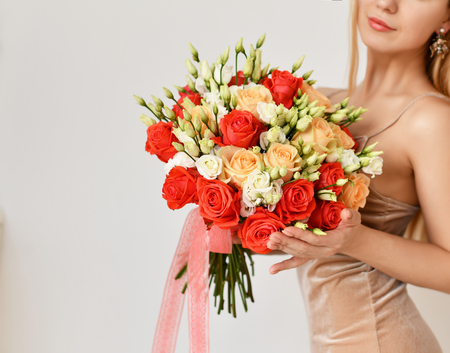 Beautiful woman hold bouquet of red and pink roses flowers happy smiling on grey backgroundの写真素材