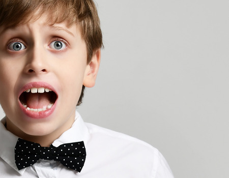Young school boy screaming and crying close up on gray backgroundの写真素材