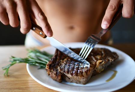 Man ready to eat cut with fork and knife grill beef steak on dark backgroundの写真素材