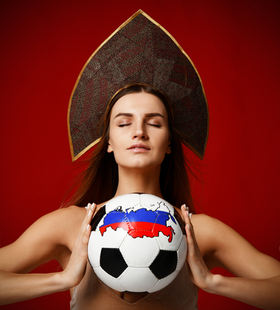 Russian style Fan sport woman player in kokoshnik hat hold soccer ball celebrating happy smiling kissing with free text copy space on red backgroundの写真素材