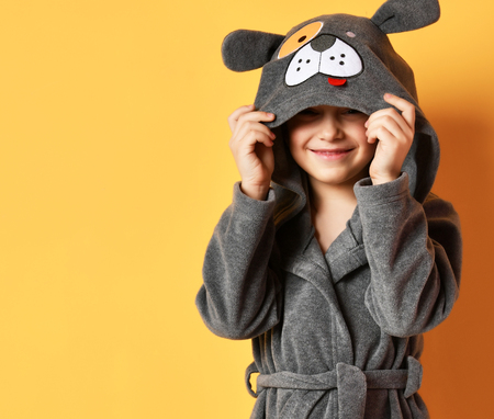 Boy kid standing in gray bathrobe looking at the corner on yellow backgroundの写真素材